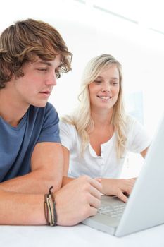 A smiling couple sitting together as they look at the laptop 