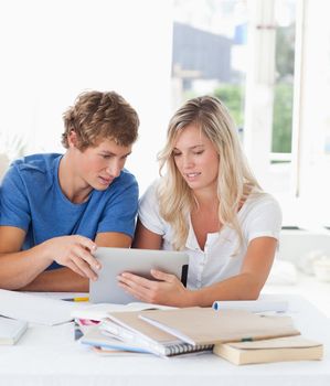 A couple look at a tablet together while doing homework