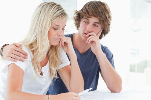 A worried couple embracing as they look at a pregnancy test 