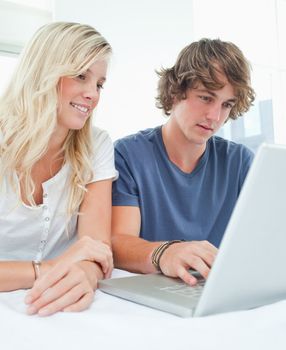 A couple using a laptop together as they sit and smile 