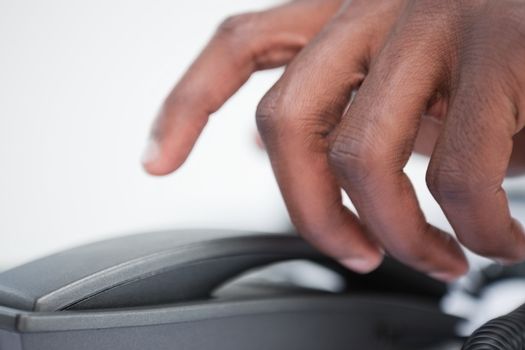 Close up of a masculine hand taking a phone handset against a white background