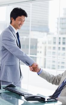 Portrait of an employee shaking the hand of his manager in an office