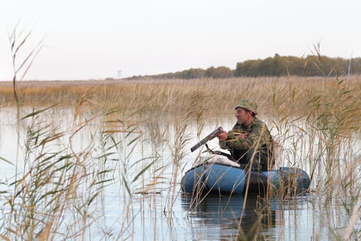 Hunter in an inflatable boat reloads gun