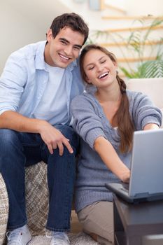 Portrait of a smiling couple using a notebook in their living room