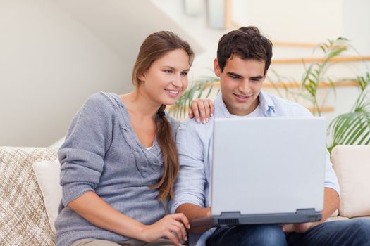 Smiling couple using a laptop in their living room