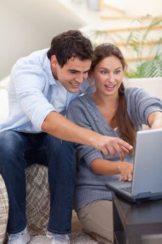 Portrait of a surprised couple using a notebook in their living room