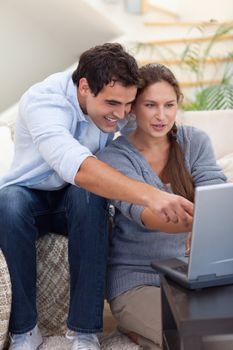 Portrait of a startled couple using a laptop in their living room