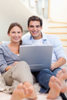 Portrait of a couple using a notebook while lying on a sofa in their living room