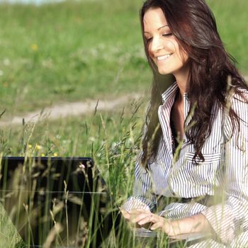 girl with laptop on green grass