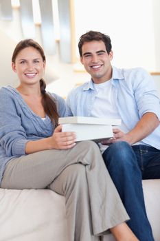 Portrait of a man surprising his fiance with a present in their living room