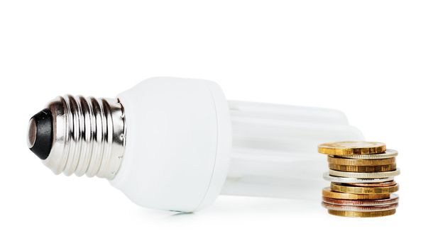 Light bulb and stack of coins over white background