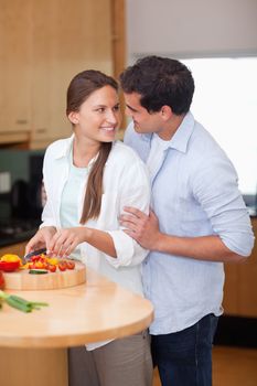 Portrait of a man hugging his wife while she is cooking in their kitchen