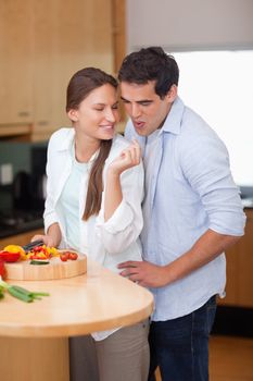 Portrait of a man blowing on his wife's finger in their kitchen