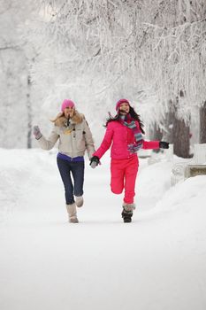 two winter women run by snow frosted alley