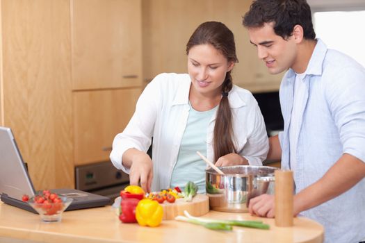 Happy couple using a laptop to cook in their kitchen