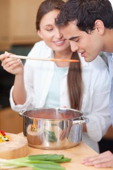 Portrait of a man trying his wife's sauce in their kitchen