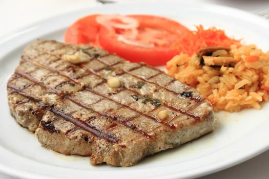 Grilled tuna steak with limpets rice and tomatoes.