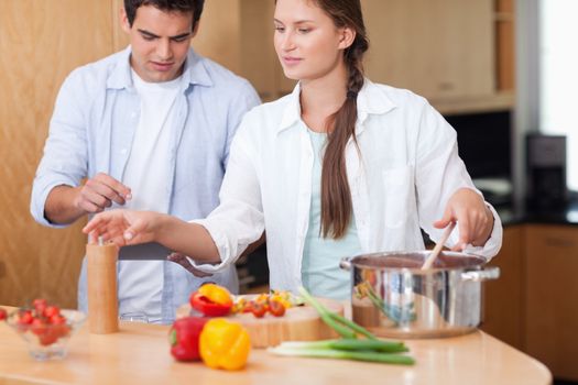 Cute couple using a tablet computer to cook in their kitchen