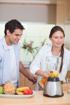 Portrait of a young couple making fresh fruits juice in their kitchen