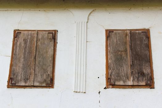 windows with wooden blinds closed, abandoned old house in Rimetea, Romania