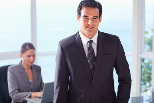 Smiling young businessman with colleague behind him