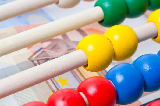 Education concept - Abacus with many colorful beads and banknotes in background