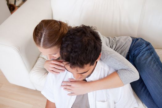 Young woman hugging her boyfriend on the sofa