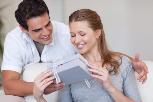 Young woman opening the gift she got from her boyfriend