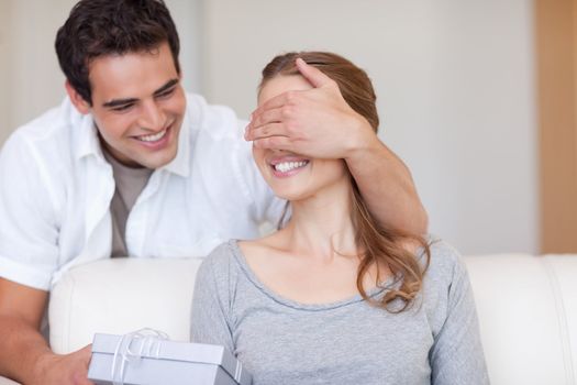 Young man surprising his girlfriend with a present