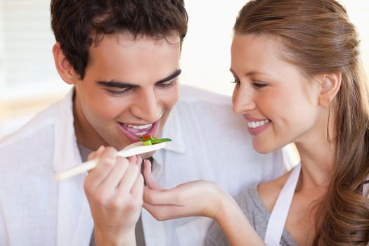 Young man is tasting the meal his girlfriend is cooking
