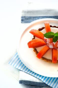 Small tarte with fresh papaya and mint as decoration on white background