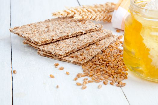 honey with a wooden spoon and crispbread on wooden background
