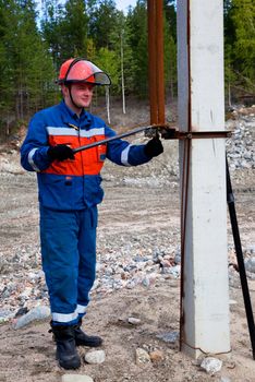 
Electrician in blue overalls makes switching. Portrait in full growth
