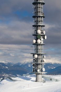 Communication antenna tower and satellite dishes against blue sky.