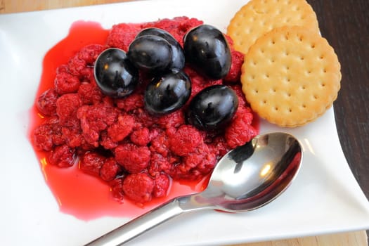 red grapes and  wild raspberry on a white plate