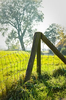 Fence on country field on hazy day in fall