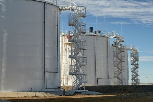 Vertical steel tanks for the storage of oil on a background of blue sky.