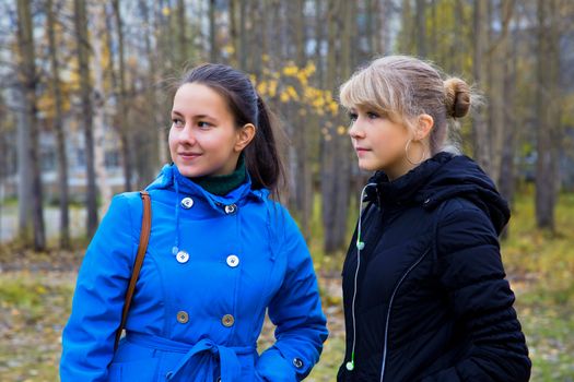 Two girls walking in the autumn park saw something interesting