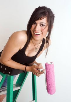 A brunette woman prepares paints the wall of her apartment