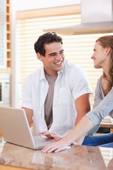 Smiling young couple with laptop in the kitchen