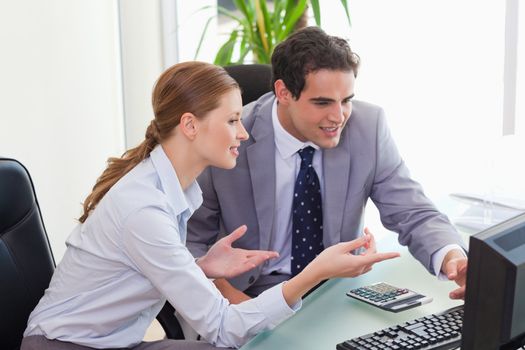 Young colleagues talking about computer problems