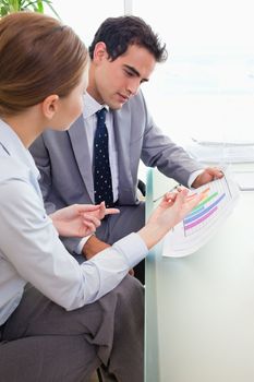 Side view of young colleagues analyzing diagram together