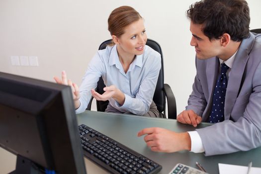 Young trading partner sitting behind a desk while talking