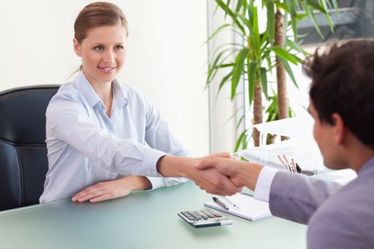 Young consultant shaking hands with her client