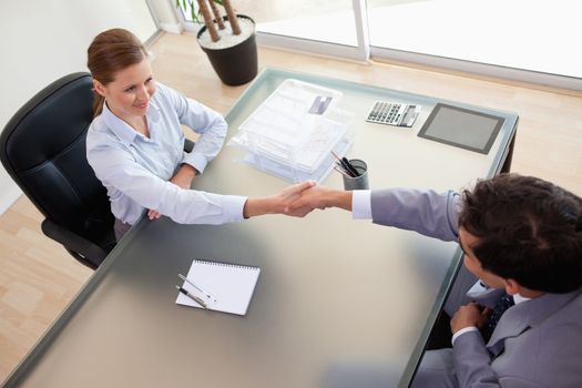 Above view of young consultant shaking hands with her client