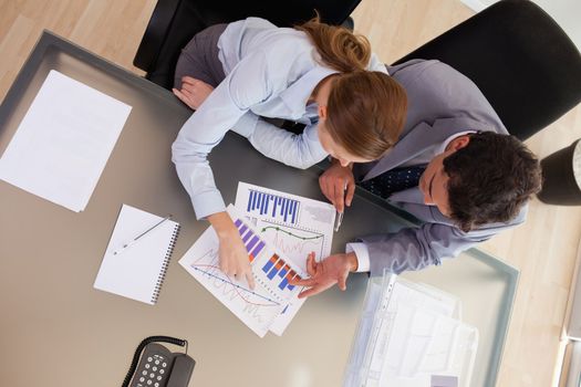 Above view of young consultant analyzing statistics with her client