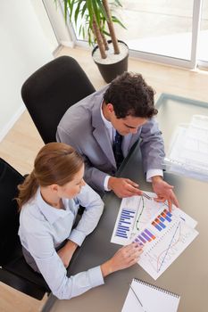 Above view of young consultant analyzing diagram with her client