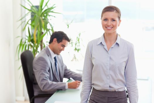 Smiling young tradeswoman with colleague sitting behind her