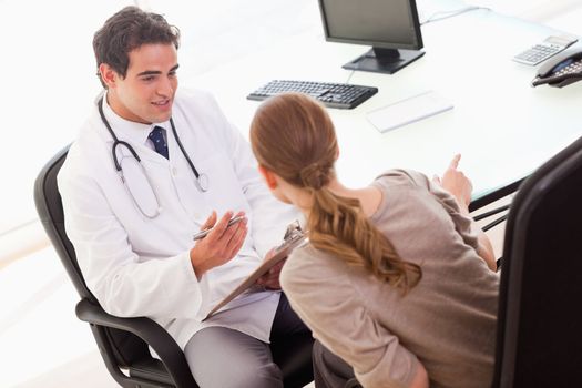 Young doctor asking his patient for symptoms 