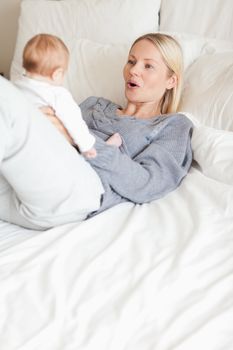 Mother playing with her baby in the bed